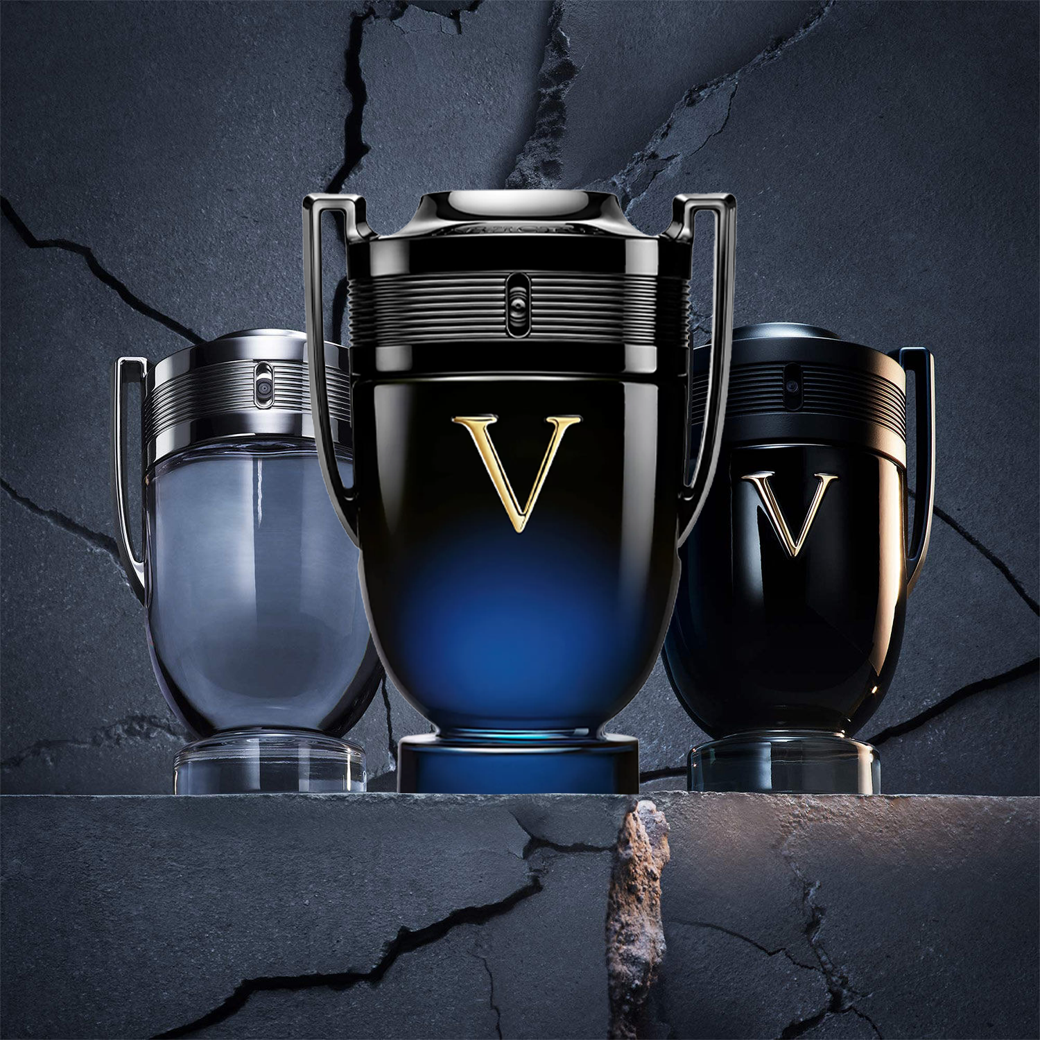 Paco Rabanne Invictus fragrance collection featuring Invictus, Invictus Victory, and Invictus Intense in trophy-shaped bottles against a cracked stone backdrop.