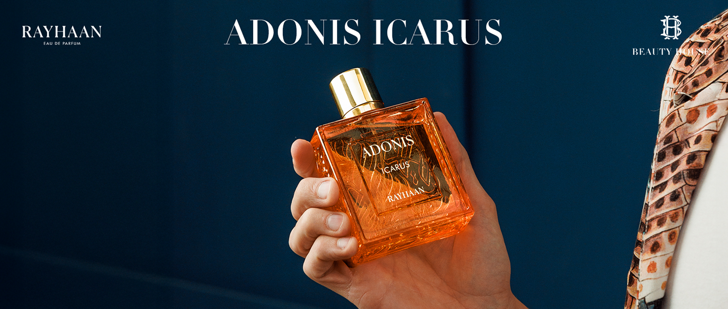 Hand holding Rayhaan Adonis Icarus perfume bottle with a golden cap against a dark blue background, featuring Beauty House branding.