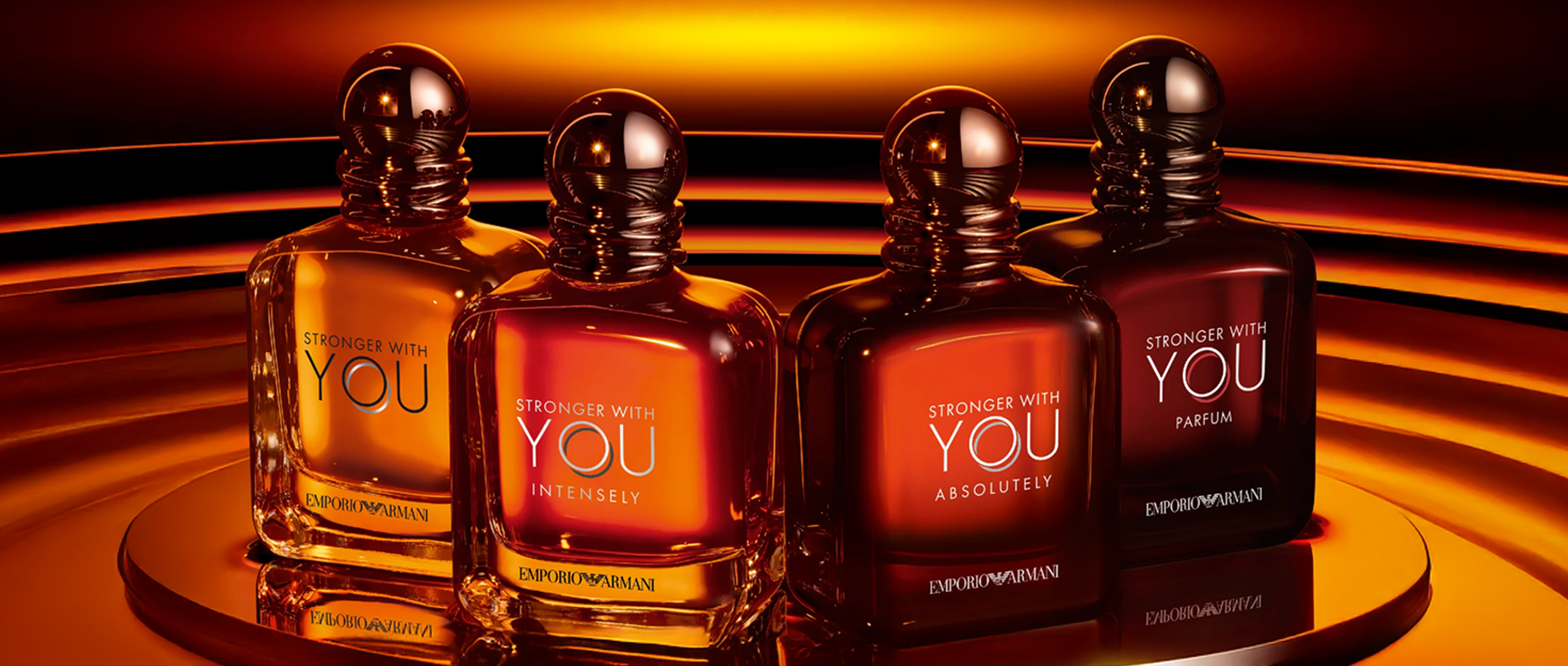 Emporio Armani Stronger With You fragrance collection featuring Stronger With You, Stronger With You Intensely, Stronger With You Absolutely, and Stronger With You Parfum bottles displayed with a glowing amber background.