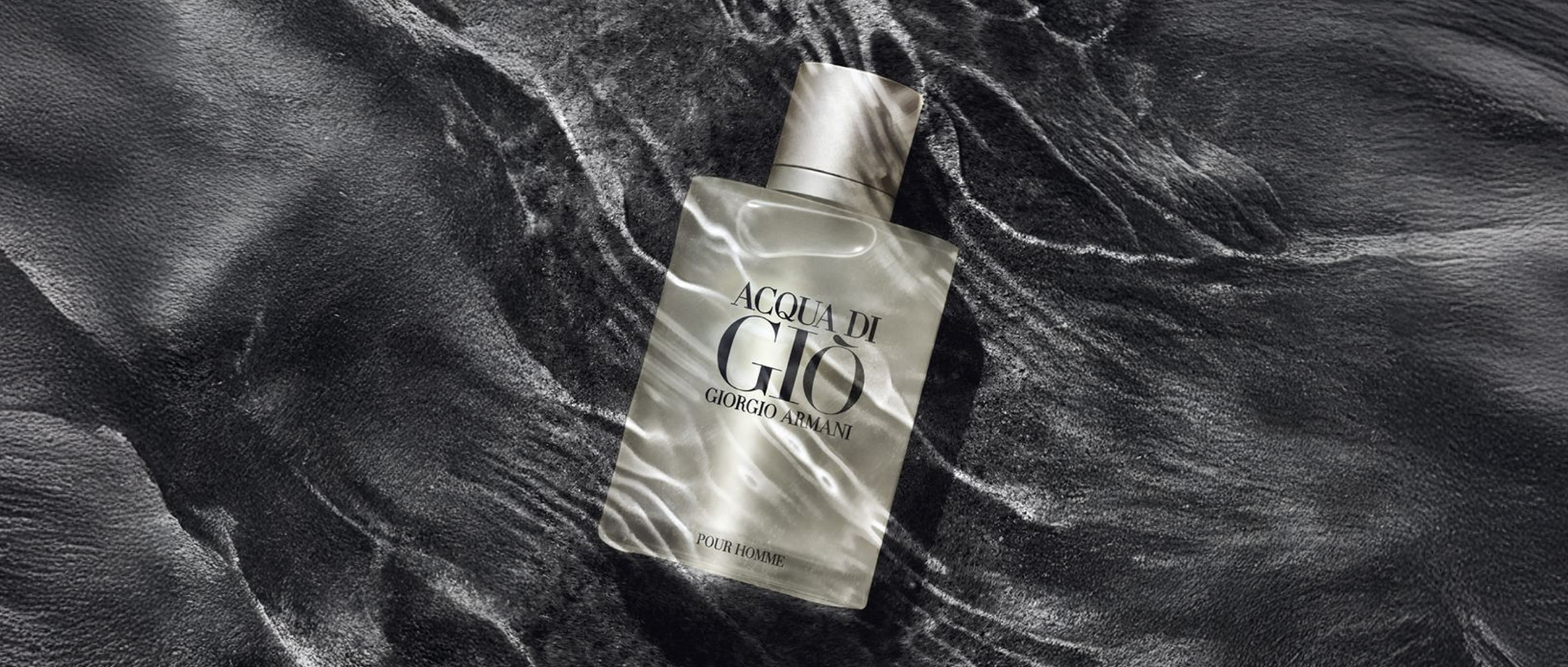 Giorgio Armani Acqua di Giò Pour Homme bottle on textured black water background, luxury men’s fragrance photography.