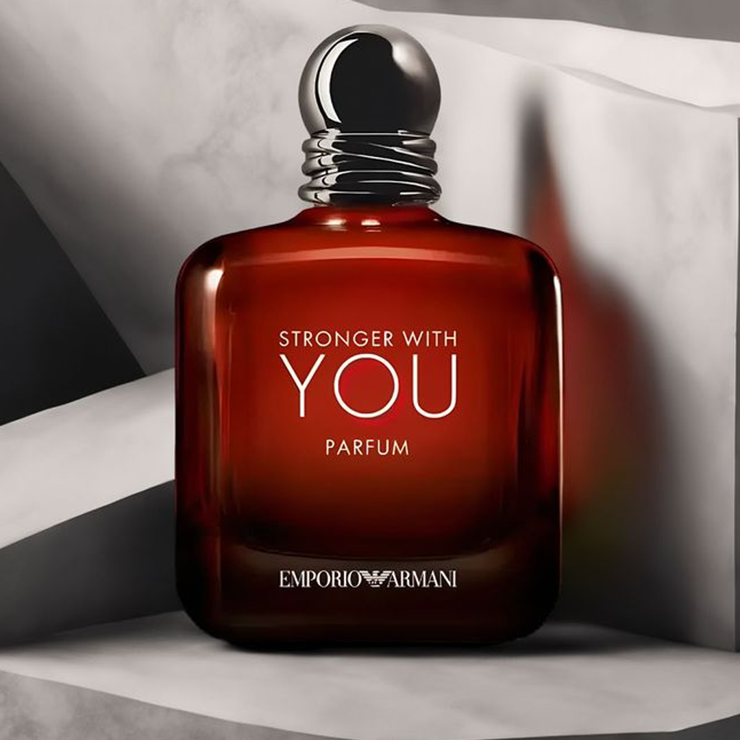 A deep amber bottle of Emporio Armani’s Stronger With You Parfum stands on a sleek gray background, exuding warmth, elegance, and modern masculinity.