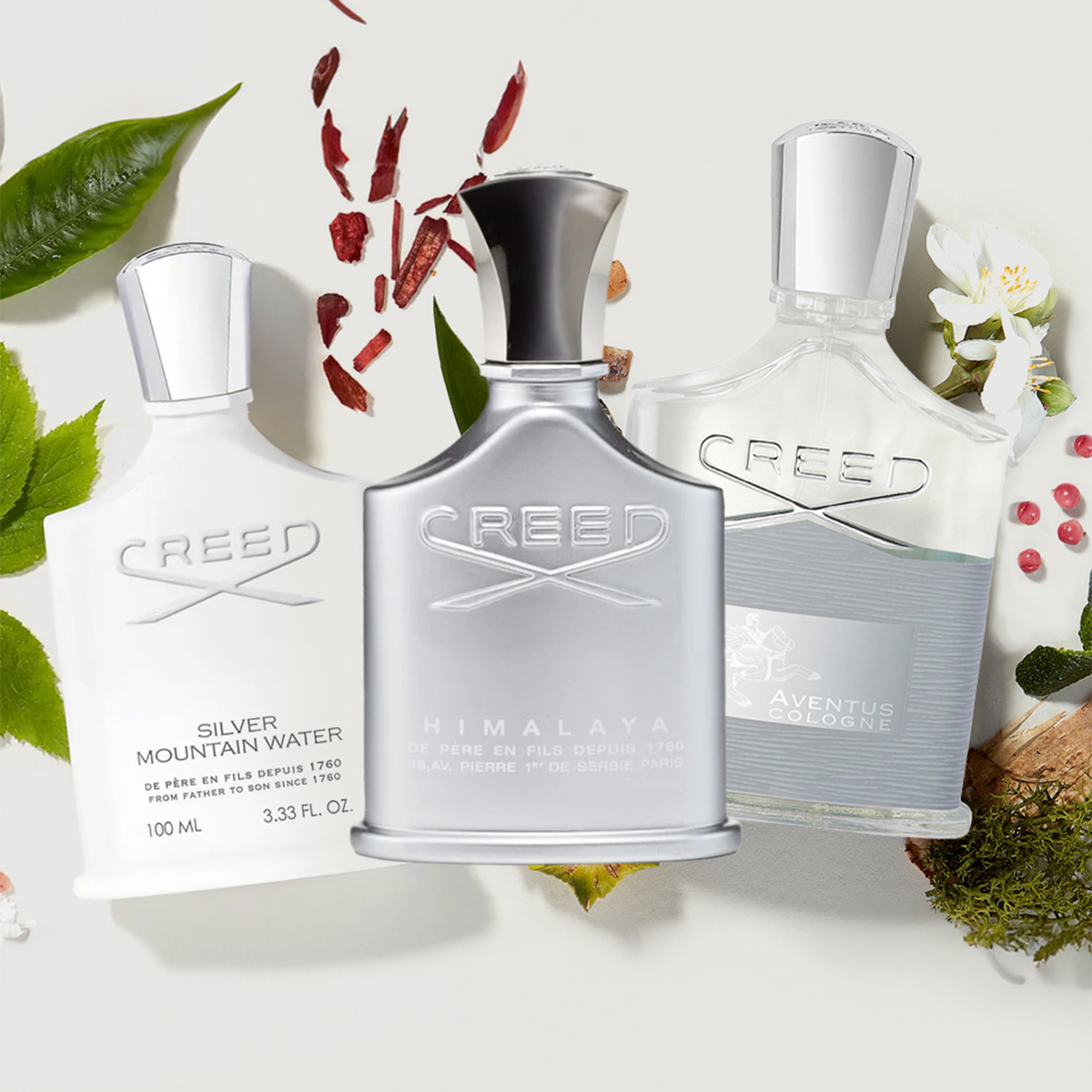 Creed Silver Mountain Water, Himalaya, and Aventus Cologne bottles displayed with natural fragrance ingredients on a white background.