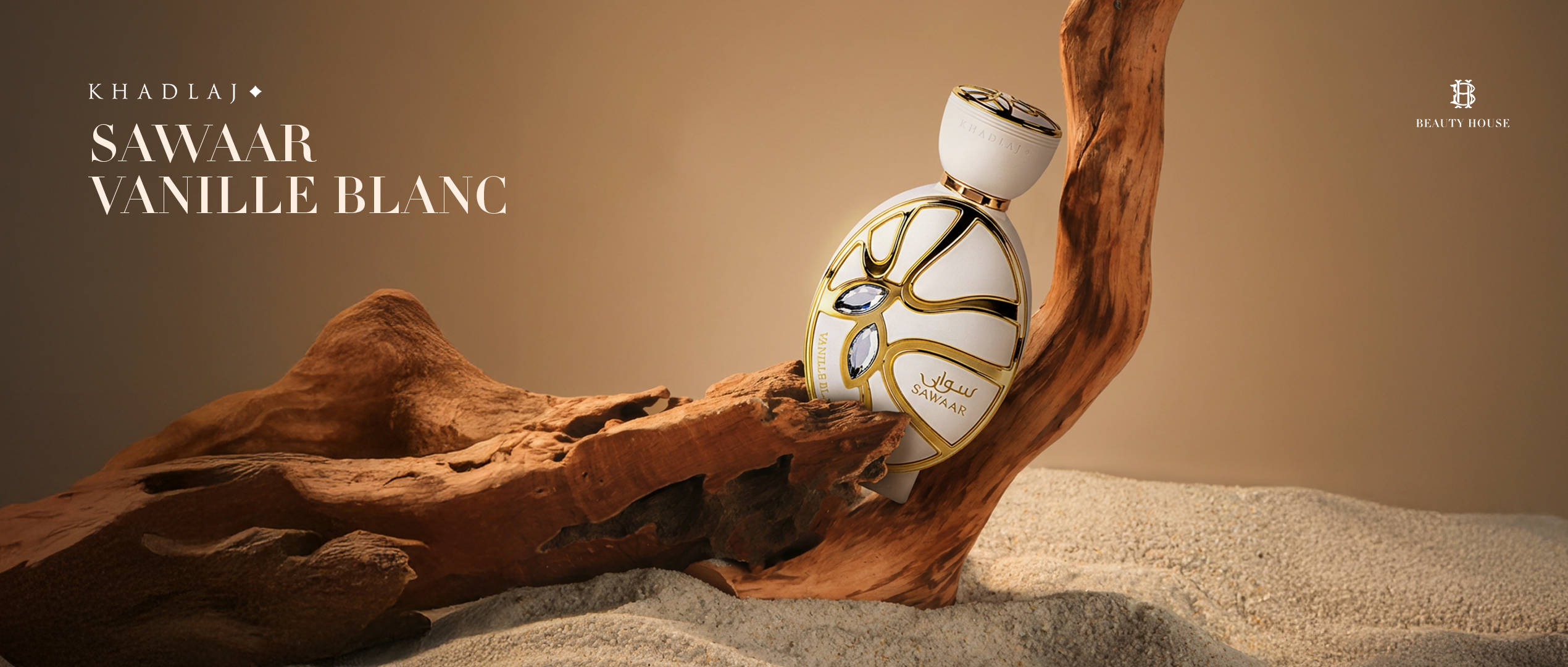 A luxurious white and gold perfume bottle sits nestled in sculpted driftwood on soft desert sand. Warm beige lighting highlights its elegant design with two blue gem accents. The banner features the text "KHADLAJ – SAWAAR VANILLE BLANC" on the left and the Beauty House logo on the right, creating a refined, earthy, and sophisticated mood.