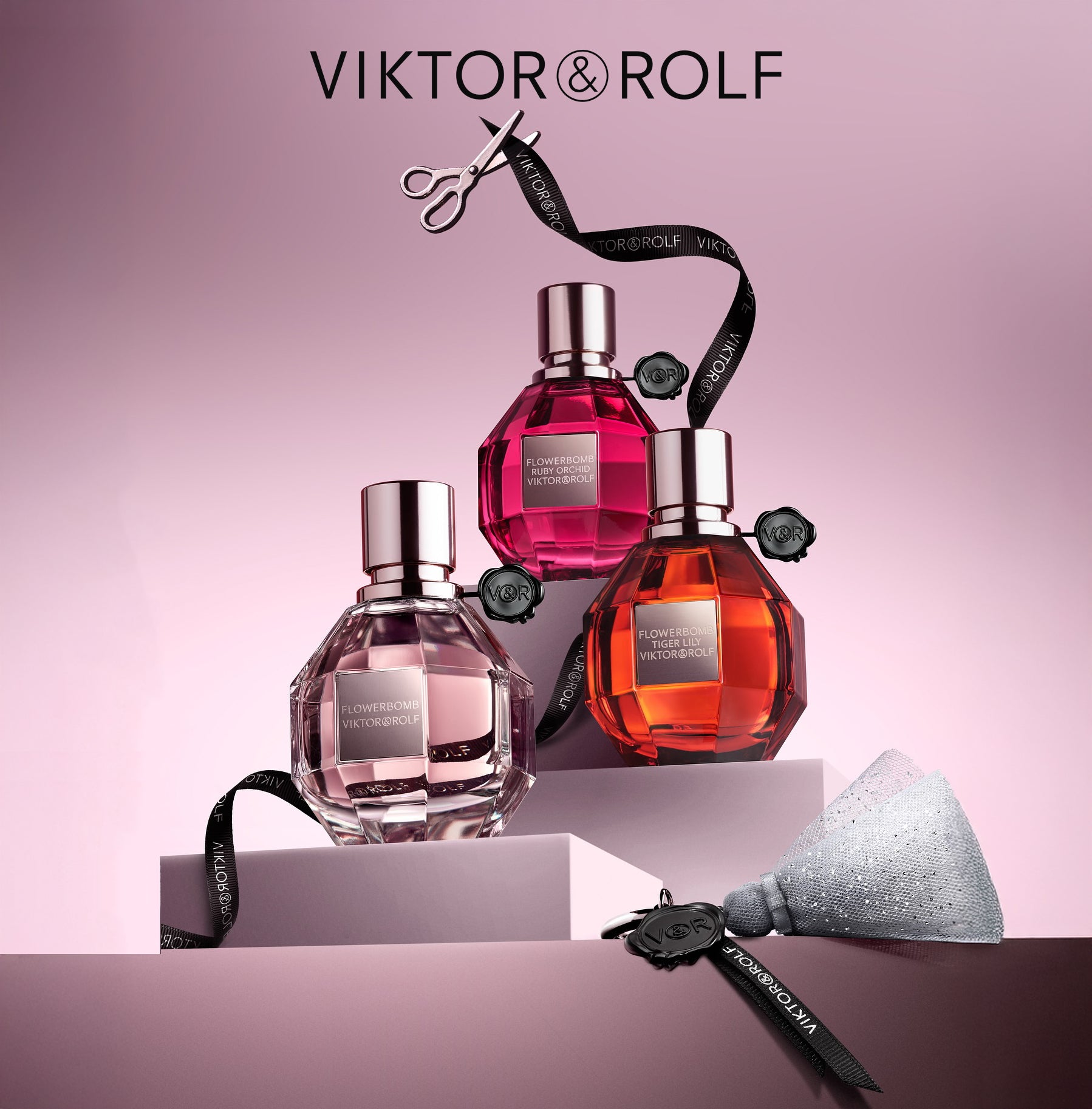 Viktor & Rolf Flowerbomb fragrance collection – luxury perfume bottles including Flowerbomb, Ruby Orchid, and Tiger Lily displayed on pink background with signature ribbon.