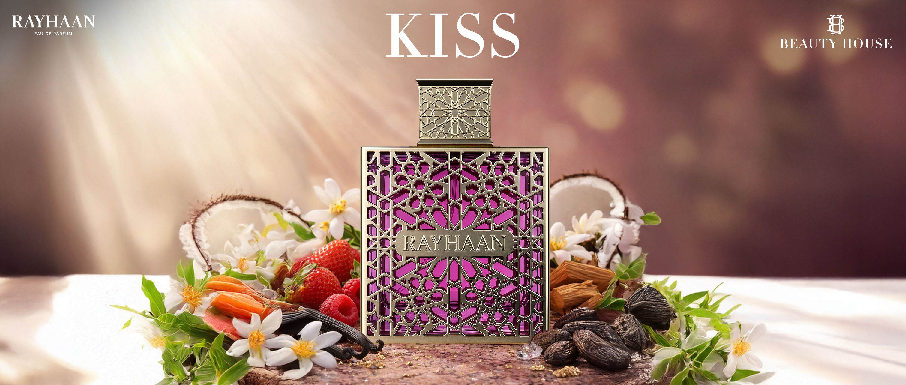 The banner shows a luxurious perfume bottle centered against a soft, dreamy background of warm beige and rose tones. The bottle is ornate, with an intricate gold lattice design revealing a bright pink liquid inside. Above it, the word “KISS” appears in elegant white text. Surrounding the bottle is a fresh arrangement of ingredients: sliced coconut, white flowers, strawberries, raspberries, vanilla pods, and tonka beans. The scene feels romantic and inviting. 
