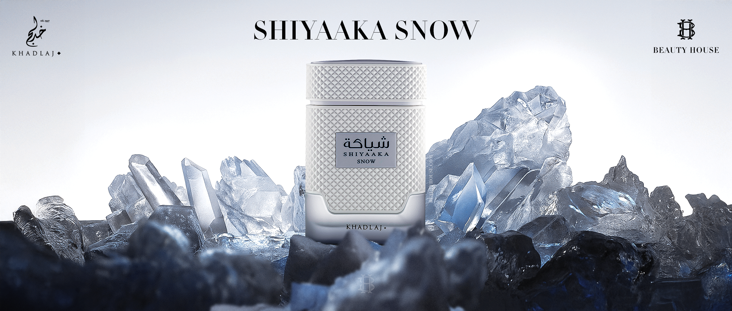 A sleek white bottle of Khadlaj Shiyaaka Snow stands amid icy blue crystals — evoking freshness, purity, and the cool sophistication of frozen elegance.