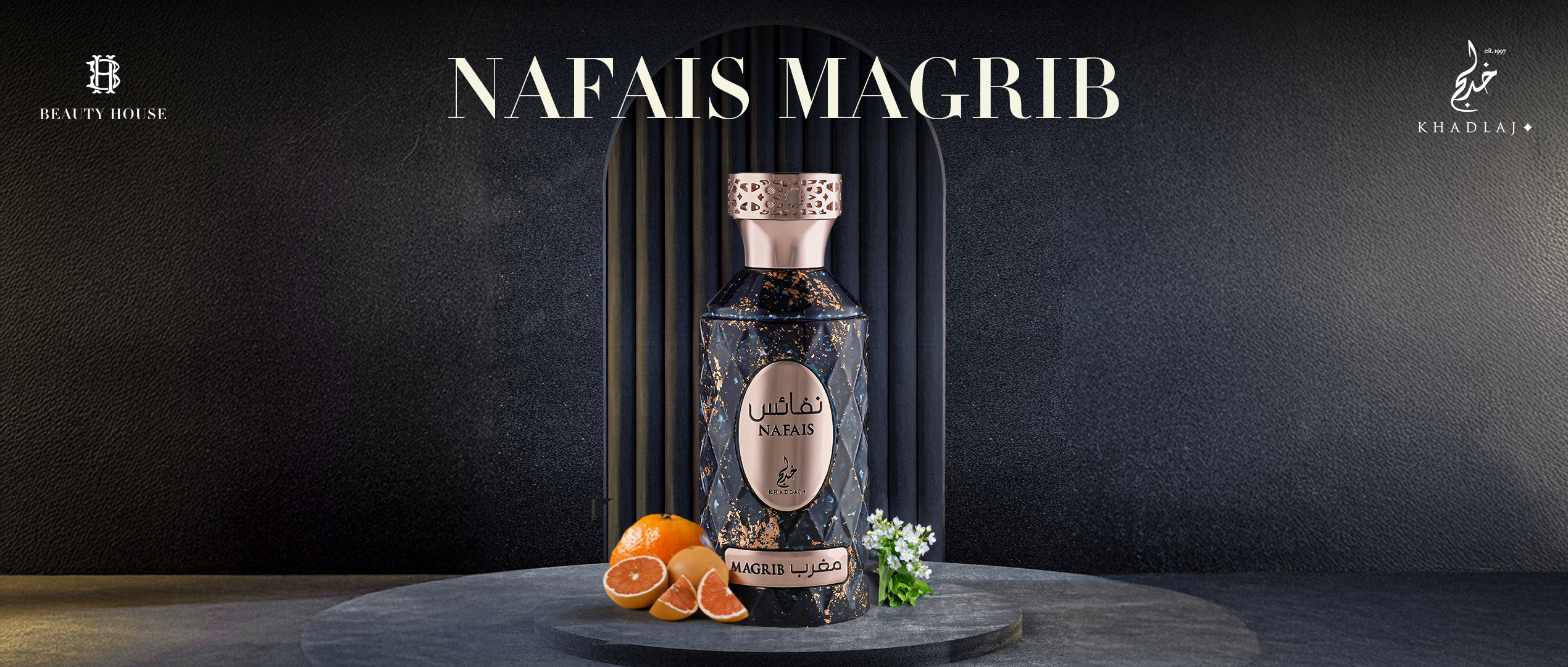 Here is a short, clean accessibility-friendly visual description in paragraph form:

The image shows a dark, elegant background with a spotlight highlighting a luxurious perfume bottle at the center. The bottle is tall and navy blue with gold marbled details and a rose-gold cap. A rose-gold oval label reads “Nafais Magrib” in English and Arabic. The bottle sits on a stone platform, surrounded by sliced oranges on the left and small white flowers on the right, suggesting fresh and aromatic notes. The Beauty 